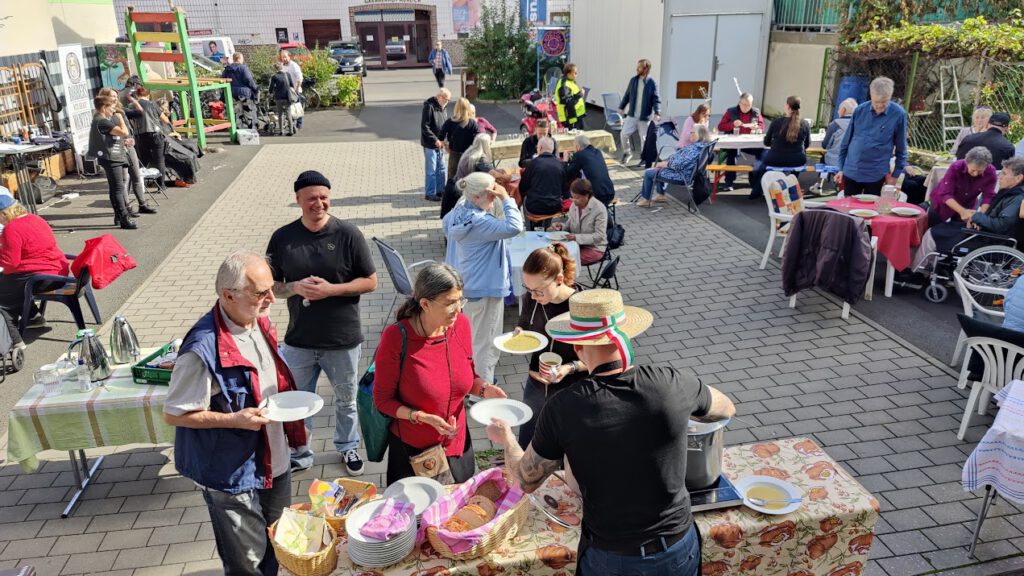 Blick auf den Hof der Werkstattkirche mit der Schlange Menschen für die Suppe